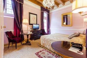 a room with a bed, chair, desk and television at Villa Cordevigo Wine Relais in Cavaion Veronese