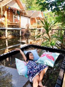 uma jovem deitada em almofadas num pátio em Nakhon Si Ban Na Homestay em Nakhon Si Thammarat