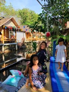 Zwei kleine Mädchen sitzen auf einem Floß neben einem Pool in der Unterkunft Nakhon Si Ban Na Homestay in Nakhon Si Thammarat