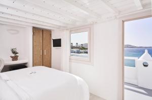 a white bedroom with a bed and a window at Little Venice Suites in Mýkonos City