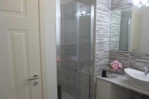 W łazience znajduje się szklana kabina prysznicowa i umywalka. w obiekcie Casa Chiocconi w mieście La Spezia