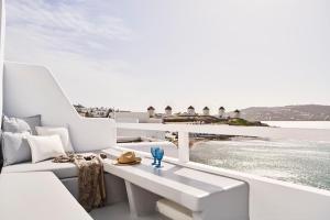 balcón con muebles blancos y vistas al agua en Little Venice Suites, en Mykonos ciudad