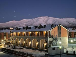 un edificio con una montaña cubierta de nieve en el fondo en Apartamentos Monte Hernanz, en Riaza