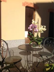 una mesa y sillas con un jarrón de flores en B&B Panemiele, en Sondrio