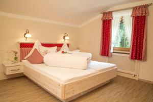 Schlafzimmer mit einem großen weißen Bett und roten Vorhängen in der Unterkunft Landhaus Notburga in Gries im Sellrain