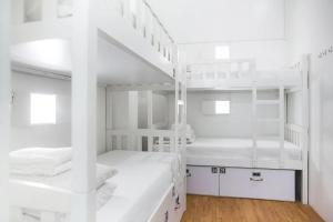 Pokój z białymi łóżkami piętrowymi i schodami w obiekcie K Hotel Aliwal (Premier) w Singapurze