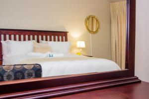 Un dormitorio con una cama con un espejo grande. en Belz Boutique Hotel, en Ixopo