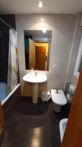 ein Badezimmer mit einem Waschbecken, einem WC und einem Spiegel in der Unterkunft Apartamentos Auhabitat Zaragoza, edificio de apartamentos turísticos in Saragossa