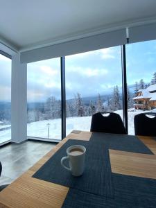 uma chávena de café sentada numa mesa em frente a uma janela em Apartamenty KADO em Karpacz