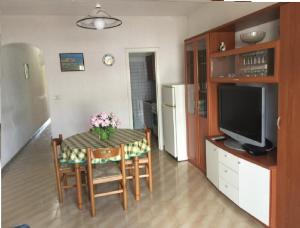 una cucina con tavolo, sedie e televisore di Marina Novaglie - 300m mare a Gagliano del Capo