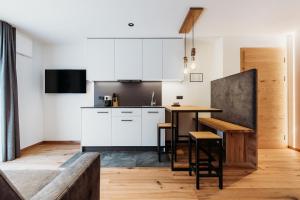 a kitchen with white cabinets and a wooden table at Höllerhof Brixen in Albes