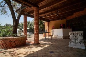 un patio de ladrillo con techo de madera y mesa en Villa San Gerardo en Piedimonte Etneo