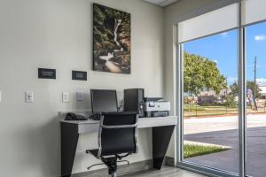 an office with a desk with two monitors and a chair at Red Lion Inn & Suites Katy in Katy