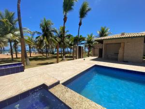 a swimming pool with palm trees and a house at Casa Tropical pé na areia in Salvador