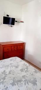 a bedroom with a bed and a dresser and a television at Canto da Cigarra I - Praia do Moçambique - FLORIANOPOLIS - SC in Florianópolis