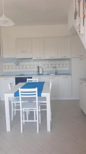 cocina blanca con mesa blanca y sillas en VILLAGGIO BOUGANVILLE en Viddalba