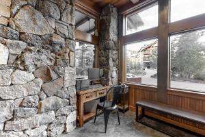an office with a stone wall and a desk and a bench at Zephyr Mountain Ski-In Ski-Out Condo in Winter Park