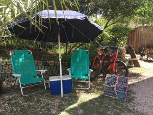 zwei Stühle und ein Regenschirm neben zwei Fahrrädern in der Unterkunft La Brújula Hostel in La Paloma