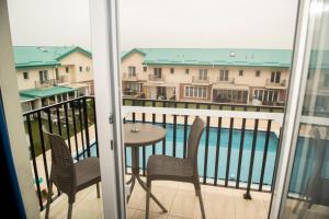 a balcony with a table and chairs and a pool at Raphael Apartment North Bucharest Cosmopolis in Ştefăneştii de Jos