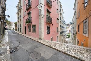 eine leere Straße in einer Gasse mit rosa Gebäuden in der Unterkunft Castle View at Lisbon Heart By TimeCooler in Lissabon
