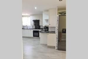 cocina con armarios blancos y nevera en Cozy Cabin en Midrand