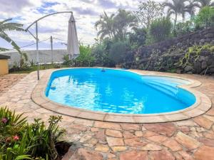 - une piscine dans une cour avec un parasol dans l'établissement TAHITI - Piafau Cottage Pool & View, à Fa'a'ā