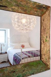 ein Spiegel, der ein Schlafzimmer mit einem Bett und einem Kronleuchter reflektiert in der Unterkunft Castle View at Lisbon Heart By TimeCooler in Lissabon