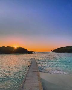 a dock in the water with the sunset in the background at VILLA VELA KSAMIL in Ksamil