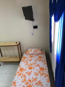 a small bedroom with a bed and a tv on the wall at Pousada Terraço Potiguara in Baía da Traição