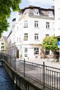 ein weißes Gebäude neben einem Fluss mit einer Brücke in der Unterkunft Altstadt Charme in Augsburg