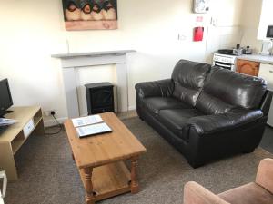 a living room with a leather couch and a coffee table at Court Farm Holiday Bungalows Ltd in Watchet