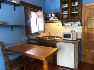 cocina con mesa de madera y microondas en Apartamentos y Casas de Aldea La Pornacal, en Villar de Vildas