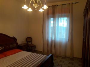 Un dormitorio con una cama y una ventana con una lámpara de araña. en Casa Carletta en San Cataldo