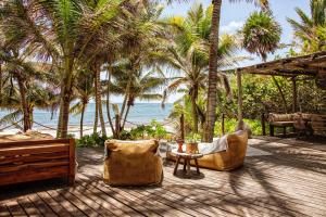 a patio with chairs and a table and palm trees at Casa Zaba in Tulum