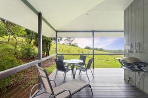 a screened in porch with a table and chairs at Alstonville Country Cottages in Alstonville