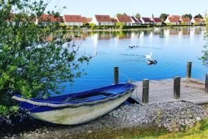 a blue boat sitting on the shore of a lake at Maison au bord de lac in Ghyvelde +7 photos