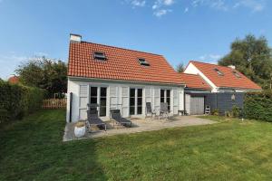 a house with two chairs and a table in a yard at Maison au bord de lac in Ghyvelde