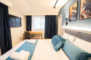 a hotel room with a large bed with blue pillows at Emil Balaban Luxury Apart-Hotel in Bucharest