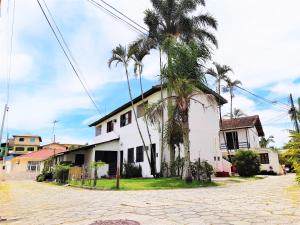 une maison blanche avec des palmiers dans une rue dans l'établissement Residencial Las Flores, à Florianópolis