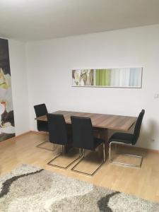 uma sala de jantar com uma mesa de madeira e cadeiras pretas em Apartament mit Balkon em Lahr