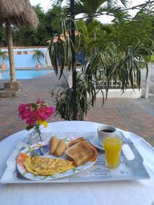 a table with a plate of breakfast food and a cup of orange juice at Hotel Coronado Inn in Playa Coronado