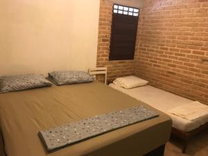 two beds in a room with a brick wall at Casa de Veraneio, com piscina, churrasqueira, área de lazer, três suites com ar condicionado a 100m da praia, na Barra de São Miguel-AL in Barra de São Miguel