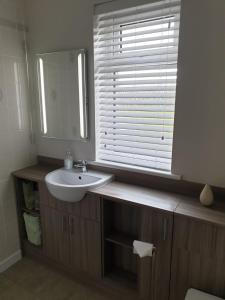 uma casa de banho com um lavatório, um espelho e uma janela em Howe Holiday homes em Stromness