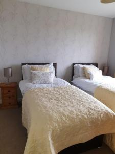 Duas camas com lençóis brancos e almofadas num quarto em Howe Holiday homes em Stromness