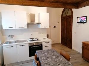 a small kitchen with white cabinets and a table at Etrusco in Chiusi