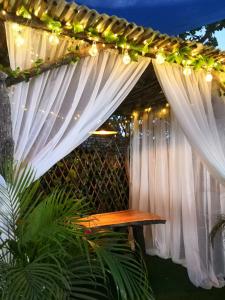 uma pérgola com cortinas brancas e um banco de madeira em Hotel Campestre Maguey em Mangue