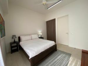 峇都丁宜的住宿－海濱公寓@溫馨海濱之家（峇都丁宜）。，一间卧室配有一张带白色床单的床和一个衣柜。