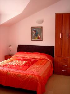 a bedroom with a red bed and a cabinet at Apartments Odalović in Bijela