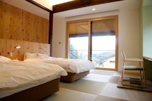 南魚沼市にあるSatoyama Jujoのベッドルーム1室(ベッド2台、窓、椅子付)