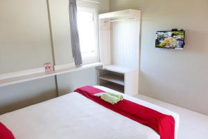 1 dormitorio con 1 cama con manta roja y blanca en Kelir Residence, en Kalibanteng-lor